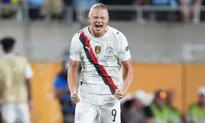 Piłkarz Manchesteru City, Erling Haaland, w białej koszulce z czerwono-czarnym pasem, świętuje bramkę.